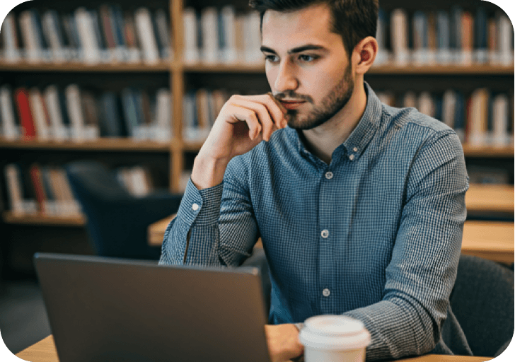 Student in a library working thoughtfully on a laptop